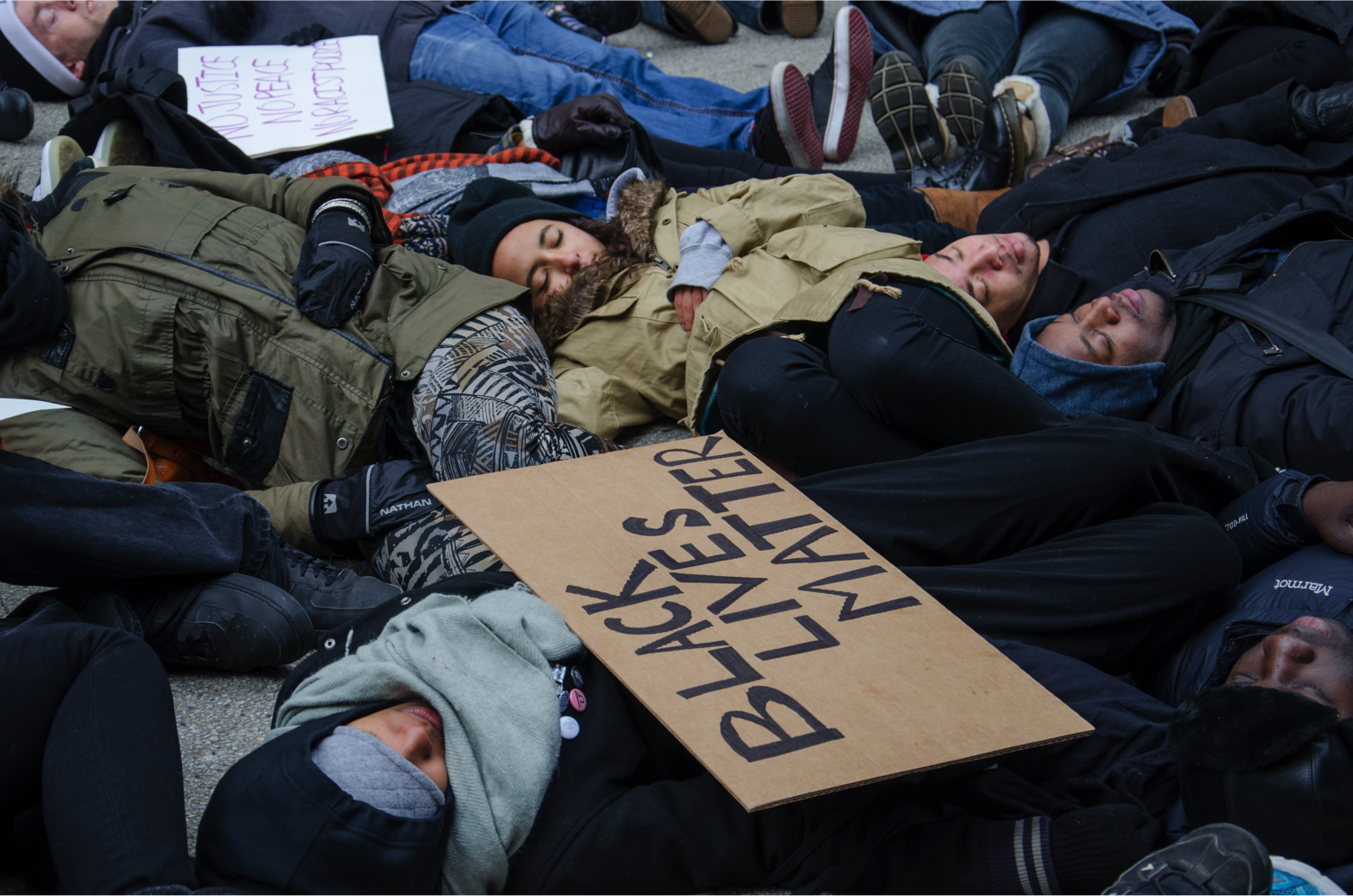 Protesters stage a “die-in” at Water Tower Plaza. 'We chose here so that we could be out here for four-and-a-half hours, which is the amount of time Michael Brown's body was left in the street,' said Kristiana Colón, director of Let Us Breathe Collective. (Jin Wu/Medill)